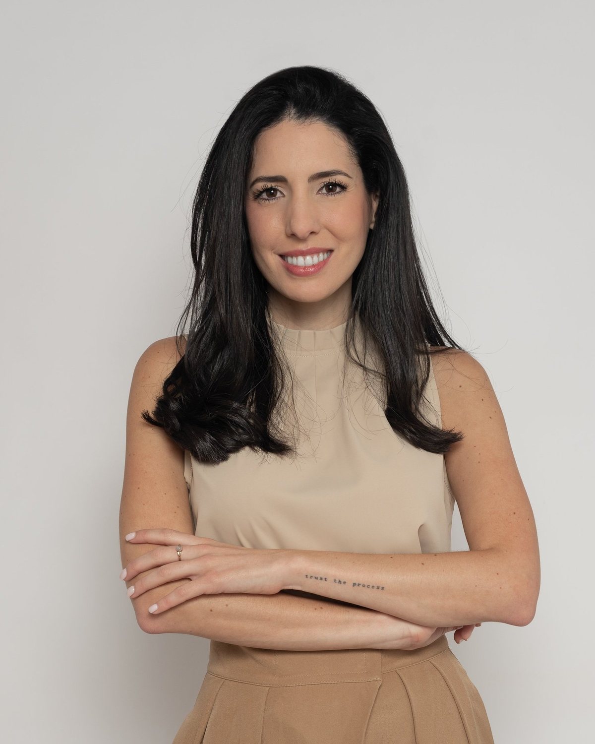 Caro Rodriguez, terapeuta holística, sonriendo con blusa beige